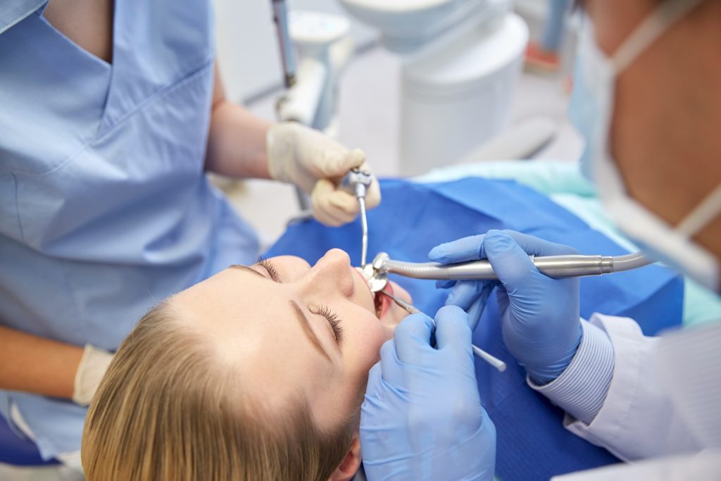 people medicine stomatology health care concept close up dentists assistant with mirror drill dental air water gun spray treating female patient teeth dental clinic
