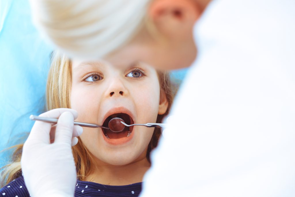 little baby girl sitting dental chair with open mouth oral check up while doctor visiting dentist office medicine concept toned photo